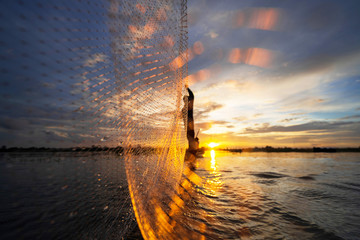 Wall Mural - Silhouette of Fisherman on fishing boat with net on the lake at sunset, Thailand