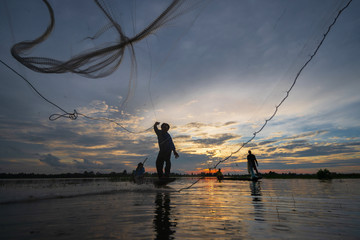 Wall Mural - Silhouette of Fisherman on fishing boat with net on the lake at sunset, Thailand