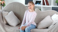 Smiling attractive European female children posing sitting on couch looking camera