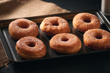 White sugar donuts on a sheet metal tray