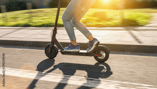 Fotografía woman riding black electric kick scooter at cityscape at summer, motion blur