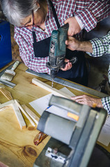 Wall Mural - Senior woman working in a carpentry workshop with her husband