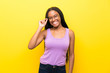 © luismolinero - African American teenager girl with long braided hair over isolated yellow wall with glasses and happy