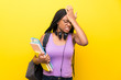 © luismolinero - African American teenager student girl with long braided hair over isolated yellow wall having doubts with confuse face expression