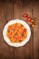 Wall Mural - Penne pasta with tomato sauce and parsley, shot from the top on a dark rustic wooden background