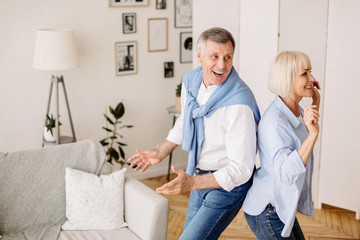 Wall Mural - Playful mature couple dancing active dance at home