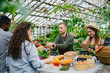 © silverkblack - Smiling salesman in apron is giving vegetables to shoppers during farm sale in greenhouse when wife is taking notes in notebook. People and business concept.