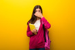 © luismolinero - Teenager student girl on vibrant yellow background covering mouth with hands