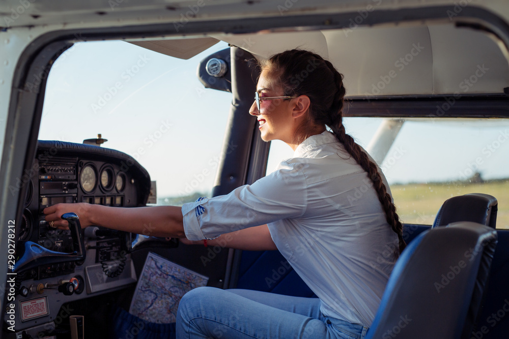 Female pilot preparing for a flight in a light aircraft - obrazy, fototapety, plakaty 