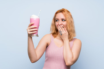 Young woman with strawberry milkshake over isolated blue background with surprise and shocked facial expression