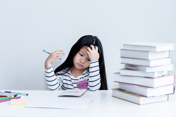 A 6 year old Asian girl, Bored of studying, homework And reading many books, with white wall background, concept to children and education.