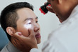 © DragonImages - Asian young man sitting at doctor's office while optometrist examining his eyes with medical lamp