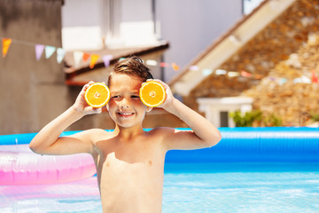 Wall Mural - Summer concept boy with oranges in swimming pool