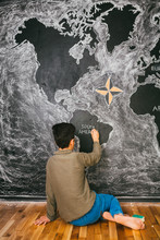 Boy Drawing World's Map In The Classroom