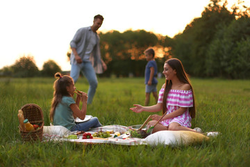 Wall Mural - Happy family having picnic in park at sunset