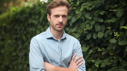 Poster - young casual man standing on the sidewalk with hands crossed, outdoor footage