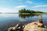 Fototapeta Big Ben - A small pyramid of stones and a bunch of strawberry berries on the shore of lake Ladoga.