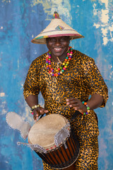 Wall Mural - Handsome african drummer weared in traditional costume playing on djembe drum