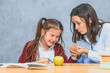 © Andrii - Mom talking to her baby. During this on a gray background. The girl cries, mom stroking her hand and talking to her daughter. Gray background. On the desk of the book and a green apple.