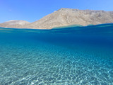 Fototapeta Most - Above and below underwater photo of crystal clear turquoise beach of Kaminakia, Astypalaia island, Dodecanese, Greece