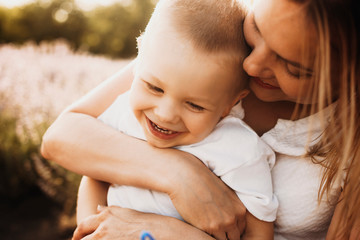 Wall Mural - close up shot of a cute little boy laughing while playing with his mother. young woman embracing her