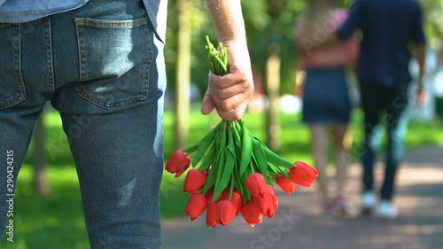 Fotografía Guy with tulips bouquet watching his girlfriend walking with another man