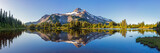 Fototapeta Natura - Volcanic mountain in morning light reflected in calm waters of lake.	