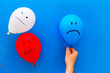 © 9dreamstudio - Negative emotions concept. Balloons with drawn faces on blue background top view