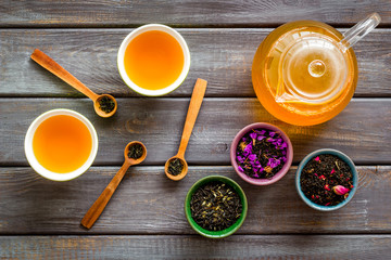 Wall Mural - Tea in pot and cups with dry leaves on wooden background top view