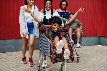 Wall Mural - Group of five african american woman with shopping carts having fun together outdoor.