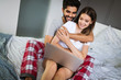 © NDABCREATIVITY - Young couple relaxing on bed with laptop. Love, technology, happiness, people and fun concept.