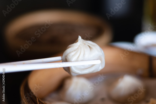 Cuadros en Lienzo Close up white chopsticks holding dim sum Ha gow over wooden basket