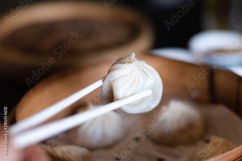 Fotomural Close up white chopsticks holding dim sum Ha gow over wooden basket