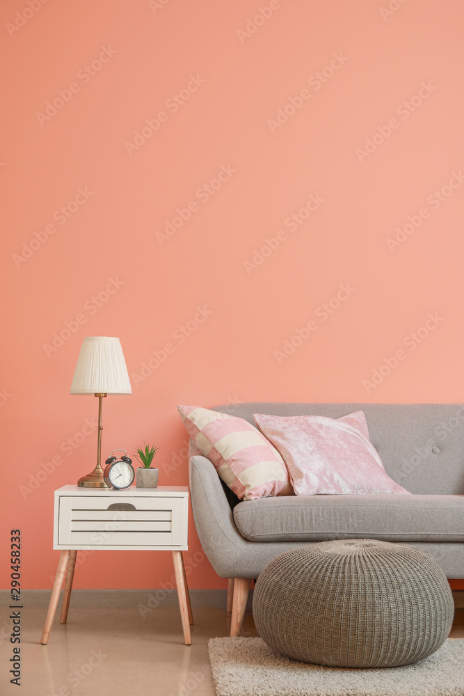 Cozy sofa with pouf and table near color wall in room