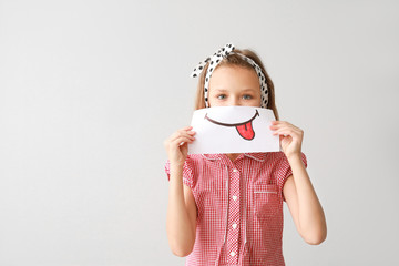 Poster - Little girl hiding mouth behind drawn smile on light background