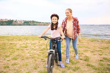 Canvas Print - Mother teaching her daughter to ride bicycle outdoors