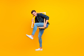 Sticker - Full length photo of crazy guy holding wooden picture frame putting leg inside it wear casual checkered shirt and jeans isolated yellow color background