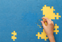 Cropped View Of Woman Matching Blue Jigsaw Puzzle On Yellow Background
