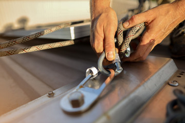 Wall Mural - Closeup pic clipping Dynamic low stretch rope rigged with figure of eight knot into screwgate locking carabiner attached into industrial stainless abseiling fall arrest roof anchor point prior to used