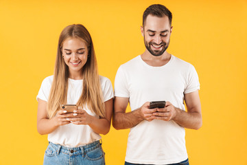 Wall Mural - Image of positive couple азsmiling while using smartphones together