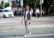 © Halfpoint - Young blind man with white cane walking across the street in city.