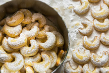 Home Baked German Austrian Traditional Christmas Cookies Vanilla Crescents In Tin Box And On Tray Powdered With Castor Sugar. Holiday Baking With Kids Sweet Treats