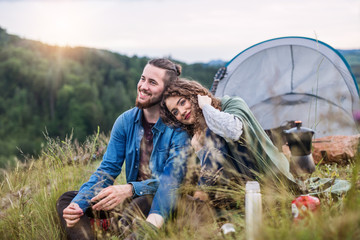 Wall Mural - young tourist couple travellers with tent shelter sitting in nature, resting.