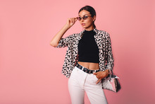 Fashion Photo Of A Beautiful Young Woman In A Casual Summer Look With Animal Print Shirt, Bag And White Jeans Posing Over Pink Background. Fashion Photo, Copy Space