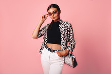 Fashion Photo Of A Beautiful Young Woman In A Casual Summer Look With Animal Print Shirt, Bag And White Jeans Posing Over Pink Background. Fashion Photo, Copy Space