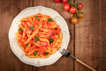 Wall Mural - Penne pasta with tomato sauce and parsley, overhead shot on a dark rustic wooden background with copyspace