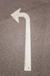 © Lukas Bast - Weißer Pfeil auf Straße zeigt abbiegen. Road sign arrow Indicating left turn.