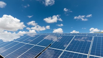 Poster - time lapse of solar power plants against a sunny sky, white clouds floating and reflected in photovoltaic panels , clean energy concept