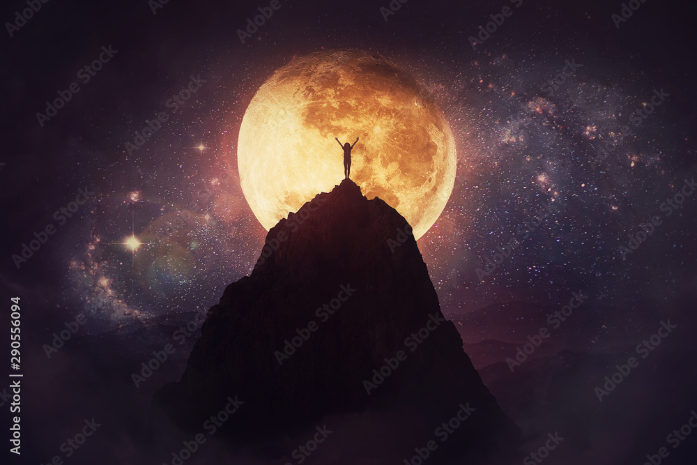 Self overcome concept as a person raising hands up on the top of a mountain over full moon night background. Conquering obstacles, success achieving. Road to win, freedom symbol. - obrazy, fototapety, plakaty 