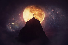 Self Overcome Concept As A Person Raising Hands Up On The Top Of A Mountain Over Full Moon Night Background. Conquering Obstacles, Success Achieving. Road To Win, Freedom Symbol.